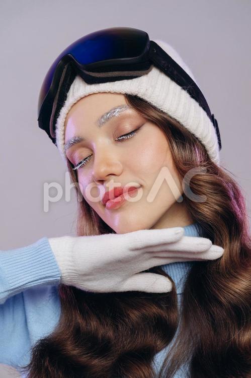 スキーの装いで目を閉じて顎に手を当てる女性 冬,スポーツ,ウィンタースポーツの写真素材