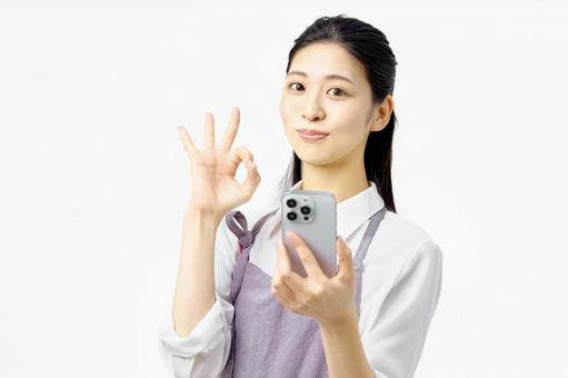 OKサインする携帯電話を持つ主婦 OKサインする携帯電話を持つ主婦の写真