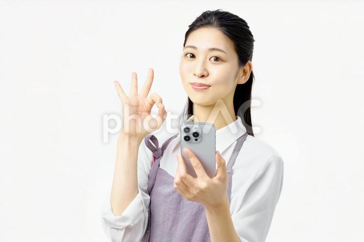 OKサインする携帯電話を持つ主婦 主婦,スマホ,okサインの写真素材