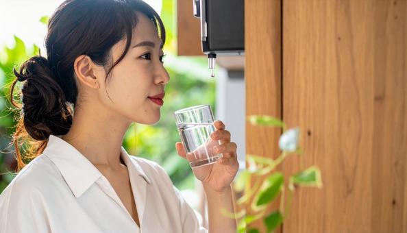 ウォーターサーバーで水を飲む日本人女性 ウォーターサーバーで水を飲む日本人女性の写真