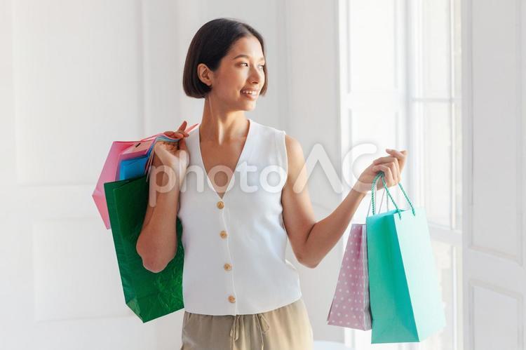 屋内でセールで買った物が入ったたくさんの紙袋を持つ女性 セール,ショップ,女性の写真素材