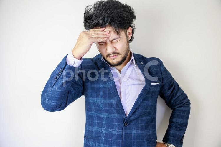 イライラと頭を抱えるスーツ姿の男性	 男性,人物,ビジネスの写真素材