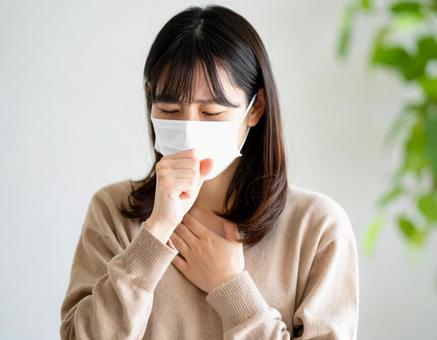 マスクを着用して咳をするの女性 マスクを着用して咳をするの女性の写真