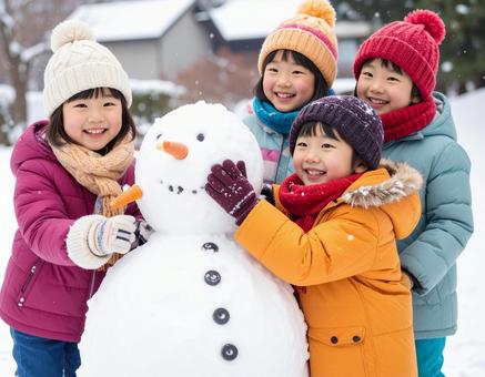 雪だるまを作って喜ぶ子供の冬の屋外風景の写真