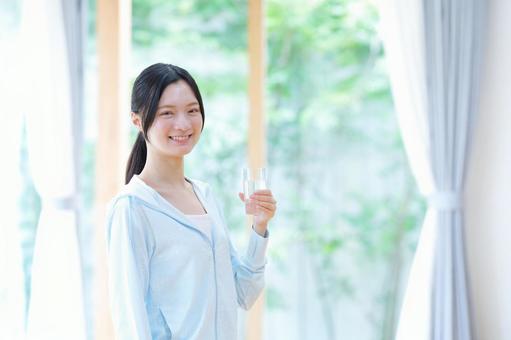 水のコップを持ち笑う女性の写真