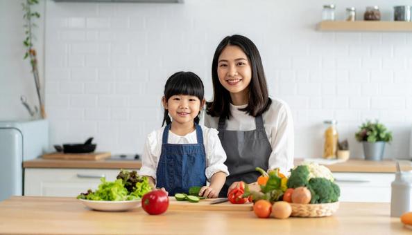 キッチンで料理をする母親と女の子 キッチンで料理をする母親と女の子の写真