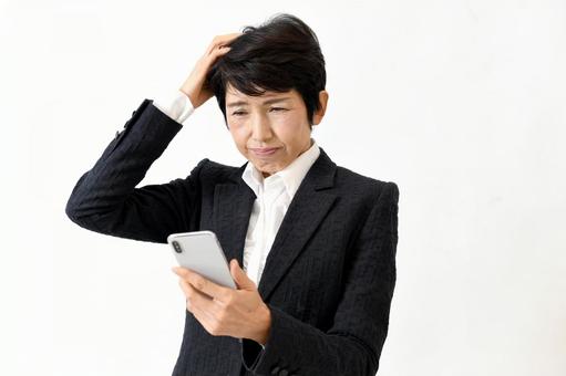 スマホ操作に困っているアジア人の中年女性 中年女性,中高年,シニア女性の写真素材