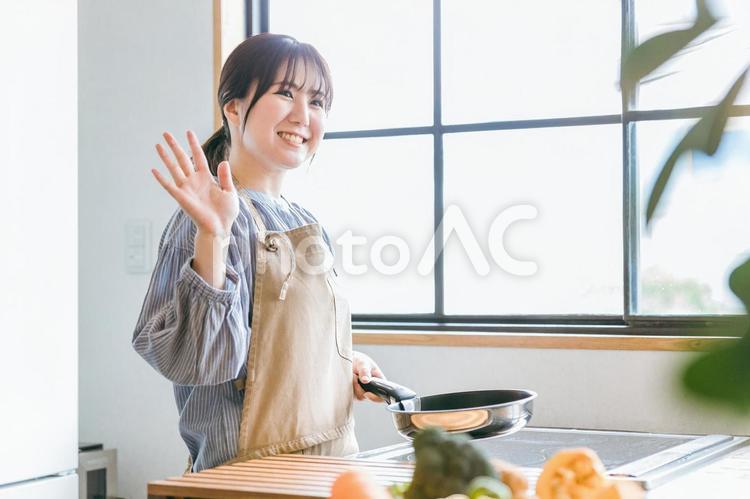 フライパンを使うエプロン姿の女性（笑顔） キッチン,料理,フライパンの写真素材