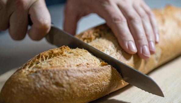 フランスパンをナイフでカットしている手元の写真