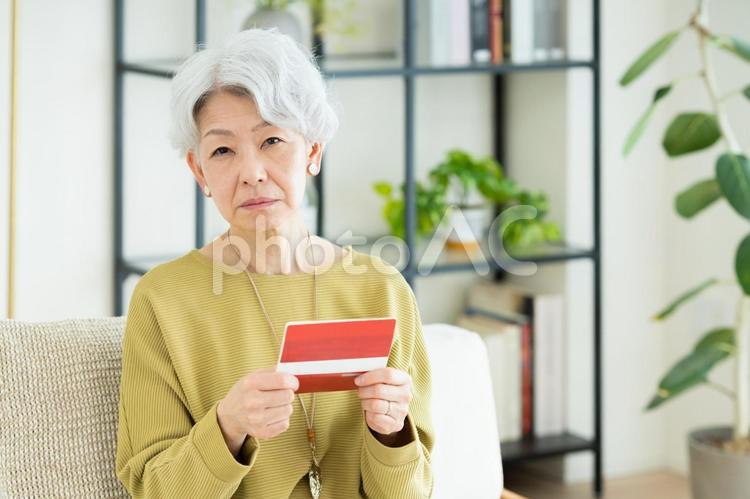 通帳を見て悩むシニアの女性 悩む,通帳,銀行の写真素材