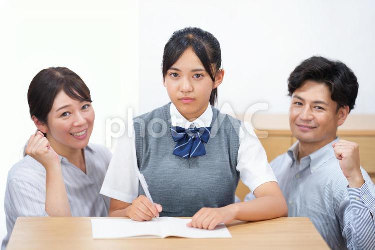 勉強する女子生徒とガッツポーズの両親 塾,人物,女の子の写真素材