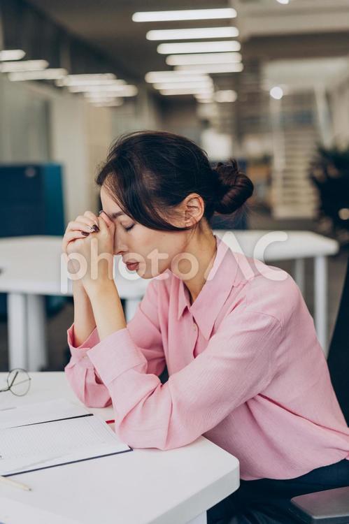 オフィスで組んだ手を額に当てて目を閉じる女性 コワーキング,ビジネス,女性の写真素材