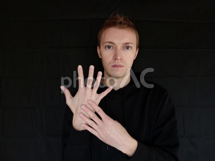 9をジェスチャーで表している外国人男性　黒バック 九,9,きゅうの写真素材