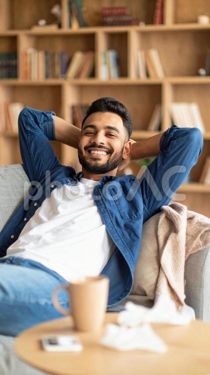 ソファで笑顔を見せるリラックスした男性 男性,リラックス,笑顔の写真素材
