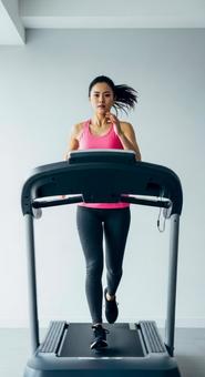 ジムでランニングマシンを使う女性 ジムでランニングマシンを使う女性の写真