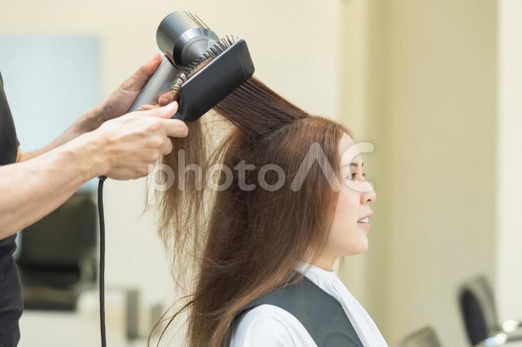ヘアサロンでドライヤーを使って髪の毛を乾かすスタイリスト ヘアサロン,スタイリスト,ドライヤーの写真素材