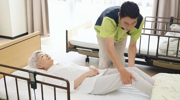 高齢者の体位変換を行うアジア人介護士 高齢者の体位変換を行うアジア人介護士 介護士,高齢者,体位変換の写真素材