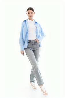 足をクロスしカメラ目線でポーズする青シャツの女性の写真