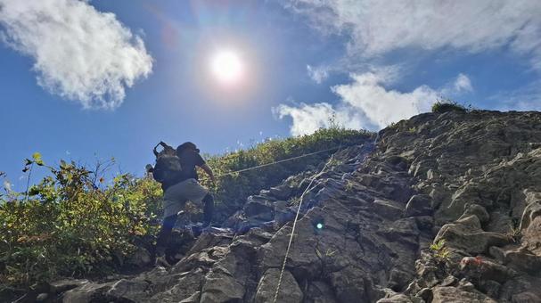 岩場をロープを使って登る登山者 鎖場,ロープ場,トラロープの写真素材