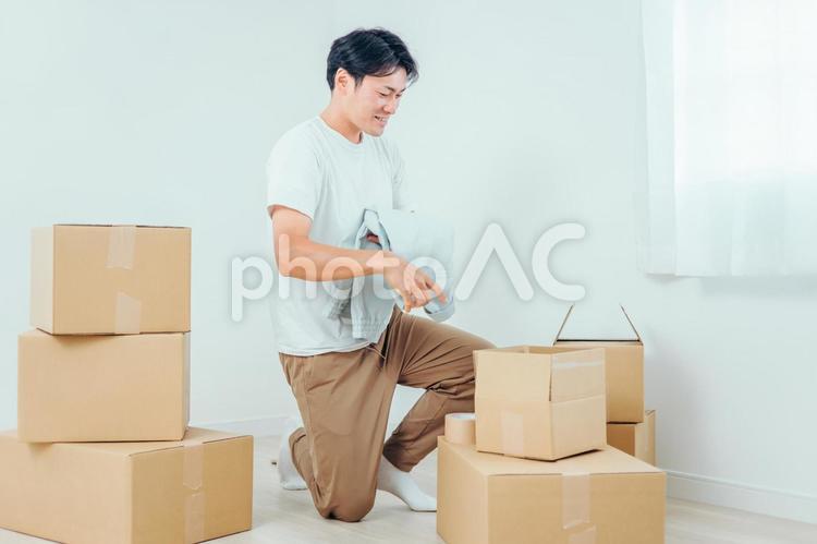 段ボールから洋服を出す男性 ダンボール,引越し,荷物の写真素材