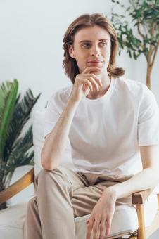 椅子に座って顎に手を当てる男性 男性,外国人,欧米人の写真素材