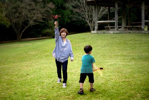 <素材>公園でおもちゃの飛行機で遊ぶ親子 <素材>公園でおもちゃの飛行機で遊ぶ親子 家族,親子,女性の写真素材