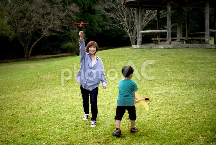 ＜素材＞公園でおもちゃの飛行機で遊ぶ親子 家族,親子,女性の写真素材