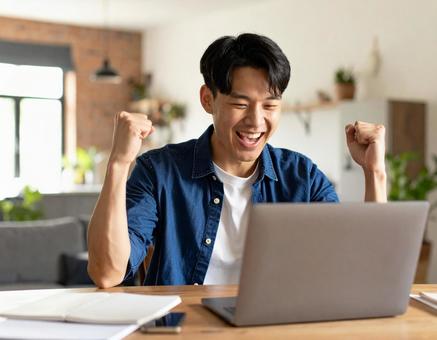 合格通知に喜ぶ若い男性のガッツポーズ 合格通知に喜ぶ若い男性のガッツポーズの写真