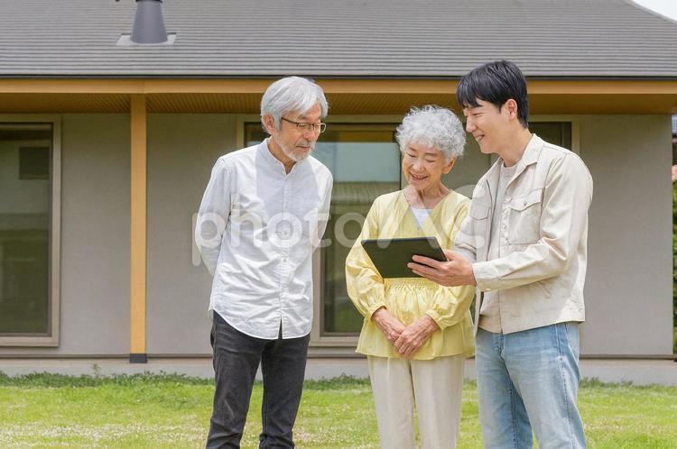 住宅の前で説明する男性作業員とシニア夫婦 シニア,夫婦,リフォームの写真素材