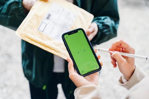 玄関で配達物の受取サインをしている画面 配達,デリバリー,配送の写真素材