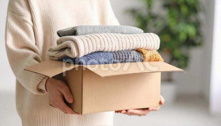 段ボールに古い衣類を詰めた女性の手 不用品,箱,女性の写真素材