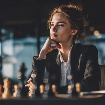チェス盤に向かう思慮深いビジネスウーマンの写真