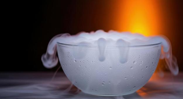 ドライアイスから煙が噴き出すガラスボウルの写真