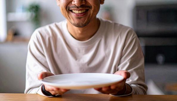 食後、空になったお皿を前に笑顔の男性 食後、空になったお皿を前に笑顔の男性の写真