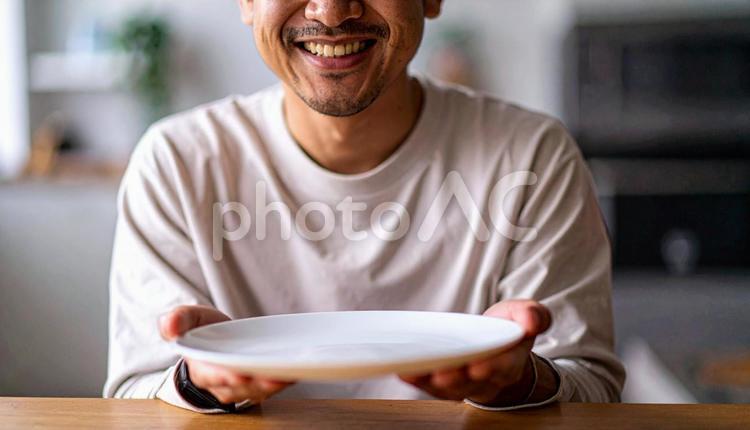 食後、空になったお皿を前に笑顔の男性 満腹,満足,食後の写真素材