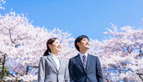 青空の下、遠くを見つめる若いスーツの男女 青空の下、遠くを見つめる若いスーツの男女の写真