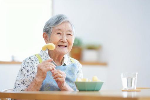 フォークに刺したリンゴを持っている高齢女性 女性,リンゴ,フルーツの写真素材