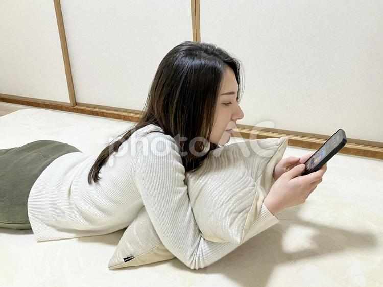 クッションを抱いてスマホをいじる女性 女性,女の子,スマホの写真素材