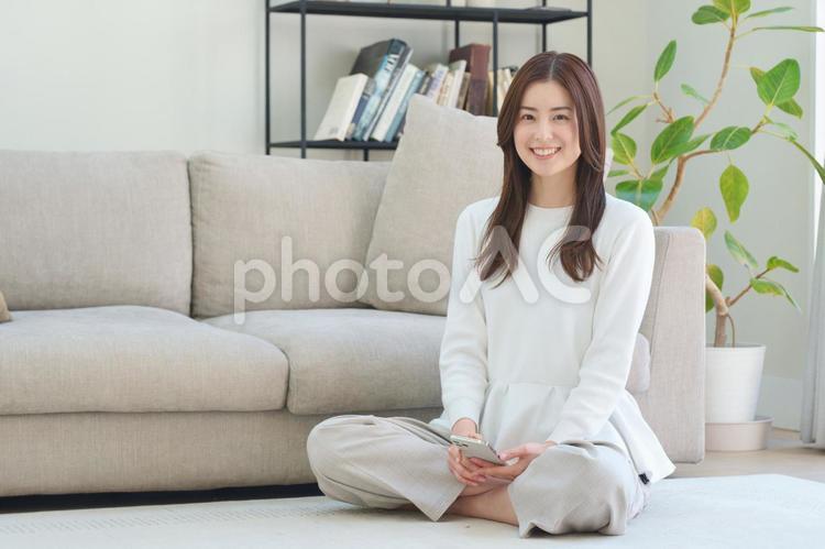リビングの床に座ってスマートフォンを使う女性 女性,日本人,大人の写真素材