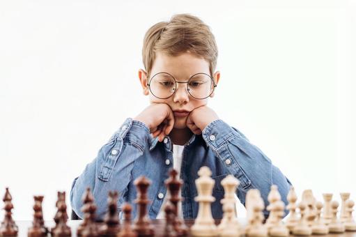 頬杖をついてチェスを見ている男の子(白背景) 頬杖をついてチェスを見ている男の子(白背景) チェス,子ども,男の子の写真素材