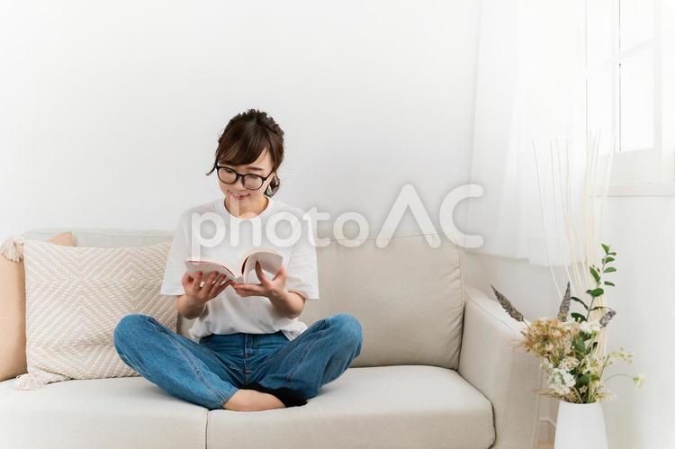 家のソファで読書するおしゃれな日本人女性 読書,本,読むの写真素材