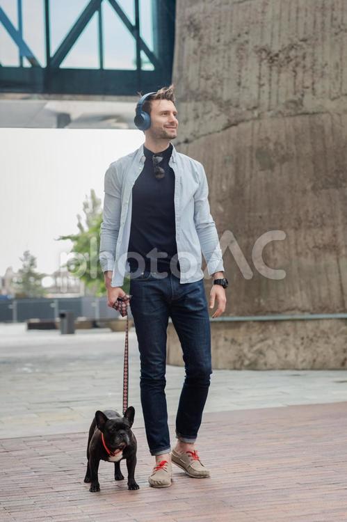 ヘッドホンをして犬の散歩をする男性 男性,犬,ペットの写真素材