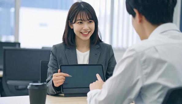 タブレットを使って説明する女性営業マン タブレットを使って説明する女性営業マンの写真