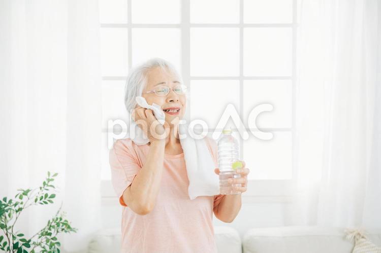 家でトレーニングする女性（水を飲む・笑顔） 高齢者,運動,汗の写真素材