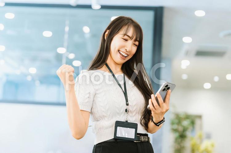 スマホを見て喜ぶ笑顔の女性ビジネスマン 女性,スマホ,スマートフォンの写真素材