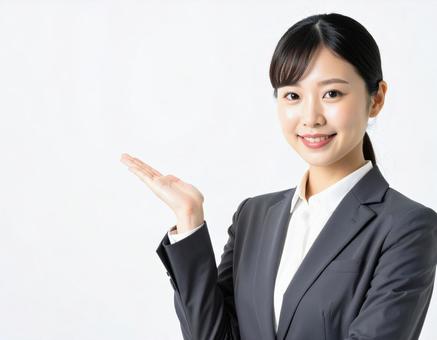 案内ポーズをするスーツ姿の女性 案内ポーズをするスーツ姿の女性の写真