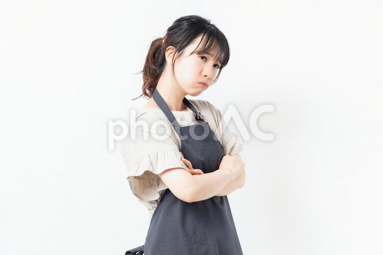 腕を組んで悩むエプロンを着た若い女性 女性,エプロン,主婦の写真素材