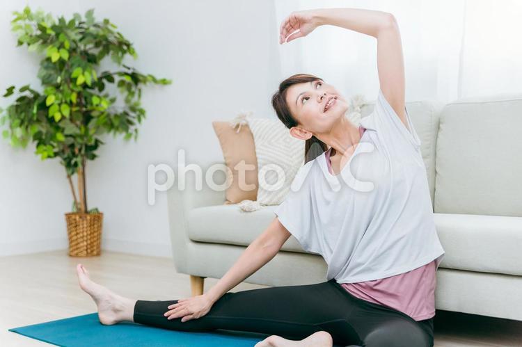 部屋でストレッチをするミドル世代の女性 ストレッチ,ヨガ,柔軟運動の写真素材