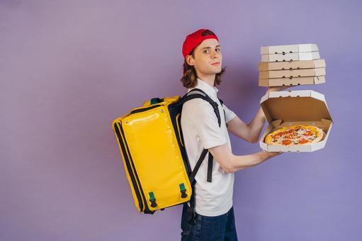 ピザを配達している男性（紫背景） 配達,フードデリバリー,デリバリーの写真素材