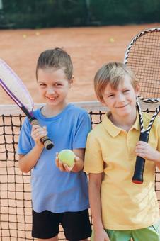 テニスネット前の子供ペア 男の子,女の子,外国人の写真素材